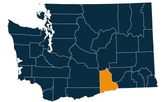 A dark blue map of Washington state with Benton County highlighted in orange.