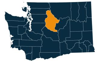 A dark blue map of Washington state with Chelan County highlighted in orange.