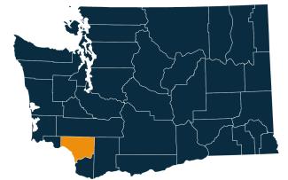 A dark blue map of Washington state with Cowlitz County highlighted in orange.