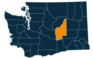 A dark blue map of Washington state with Grant County highlighted in orange.