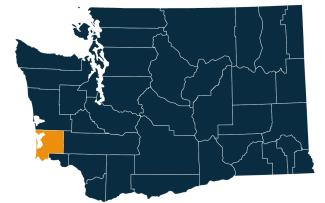 A dark blue map of Washington state with Pacific County highlighted in orange.