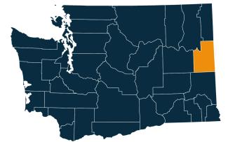 A dark blue map of Washington state with Spokane County highlighted in orange.