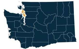 A dark blue map of Washington state with Island County highlighted in orange.