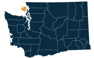 A dark blue map of Washington state with San Juan County highlighted in orange.