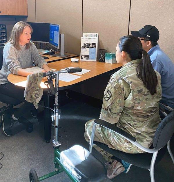 Jo Ann Enwall, an employment specialist at WorkSource Joint Base Lewis-McChord, talks with two customers in her office