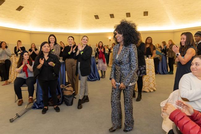 ESD’s Sanyu Tushabe stands in front of a crowd while being honored at the statewide awards for women leaders.