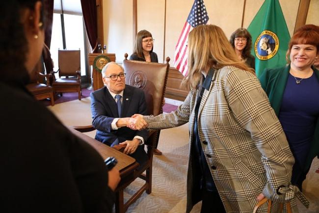 Gov. Jay Inslee shakes hands with ESD Commissioner Cami Feek after signing HB 1975 at the Capitol on March 3, 2024.